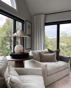 a living room with two couches and a table in front of large windows overlooking trees