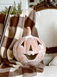 a carved pumpkin sitting on top of a couch next to a blanket and a pen