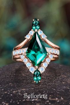 an emerald colored ring with white diamonds on top and gold band around the band, sitting on a rock