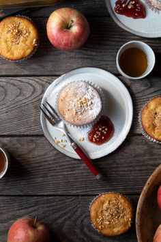 apples and muffins are on the table next to each other with jam in them