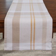 a plaid table runner on top of a wooden table with white and yellow stripes down the middle