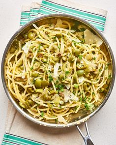 a pan filled with pasta and olives on top of a blue and white towel