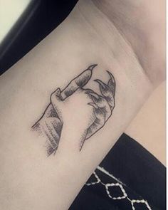 a black and white photo of a wrist tattoo with a hand holding something in it