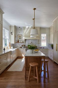 a large kitchen with white cabinets and wooden stools in the center island, along with an area rug that matches the hardwood flooring