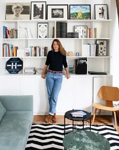 a woman standing in front of a bookshelf filled with lots of books and pictures