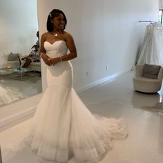 a woman standing in front of a mirror wearing a wedding dress