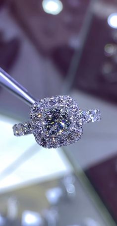 a diamond ring is being held up by a pair of tongs in front of a glass display case