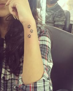 a woman with a dog paw tattoo on her left arm and the other hand behind her head