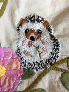 a hedgehog with flowers on it's back is sitting next to a flower