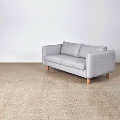 a gray couch sitting on top of a carpeted floor next to a white wall