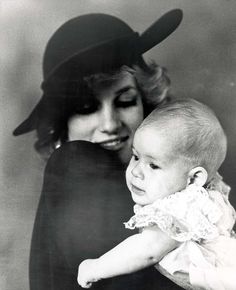 a woman holding a baby in her arms and wearing a hat on top of her head