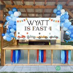 an outdoor stage set up with balloons, streamers and cars on it that says wyatt is fast 4