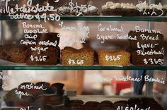 there are many different types of cakes on the shelves in this bakery display case with price signs