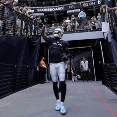 a football player is walking on the field with his foot in the air and people watching from the stands