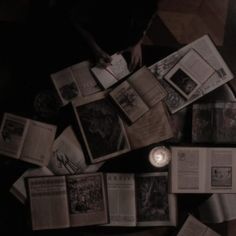 an overhead view of several books and a candle on a table in a dark room