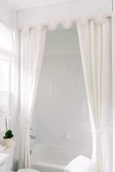 a white bathroom with pink accents and curtains