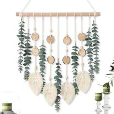 a white and green wall hanging with wooden discs, leaves and other things on it