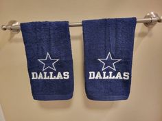 two blue towels hanging on a towel rack with the word dallas written in white letters