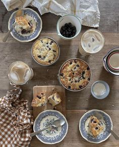 a table topped with plates and bowls filled with desserts next to cups of coffee