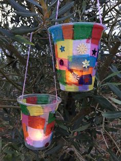 two buckets hanging from a tree with lights in them and some leaves on the ground