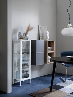 a room with a table, chair and shelf in the corner next to a window