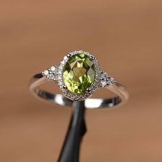 It is a natural peridot ring. The main stone is 6mm*8mm oval cut, weight about 1.33carats. The basic metal is sterling silver and plated with rhodium. To change the metal to a solid gold (white/rose) or platinum is also available, please ask for a quotation if you want. You can also go to my shop Home for more elegant rings: https://www.etsy.com/shop/godjewelry?ref=hdr_shop_menu More rings: https://www.etsy.com/shop/godjewelry?ref=l2-shop-header-avatar Customization is always welcome and please Peridot Rings, Peridot Engagement Rings, Graduation Rings, August Birthstone Ring, Gorgeous Rings, Birthstone Rings, Peridot Jewelry, London Blue Topaz Ring, Peridot Stone