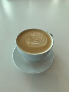 a cappuccino on a saucer with a leaf drawn in the foam