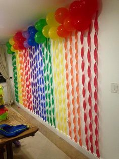 a room filled with balloons and streamers on the wall next to a wooden table