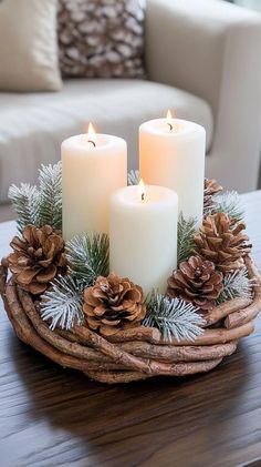 three candles are sitting in a basket with pine cones