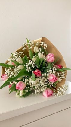 a bouquet of tulips and baby's breath sits on a white table