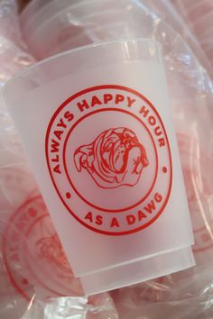 there is a plastic cup with the logo of a bulldog on it and red lettering that says always happy hour as a dawn