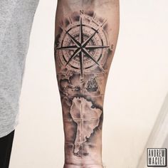 a man's arm with a compass and world map tattoo on the left forearm