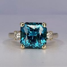 a blue diamond ring with three diamonds on the sides and one stone in the middle