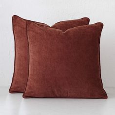 two brown velvet pillows sitting on top of a white table