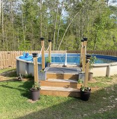 an above ground pool with steps leading up to it and potted plants in the foreground