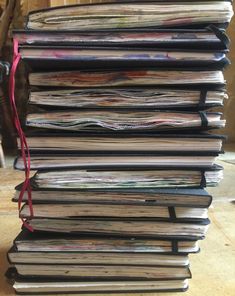 a large stack of papers sitting on top of a wooden table next to a red ribbon