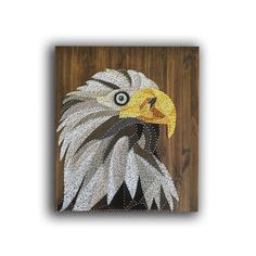 an eagle made out of beads on a wooden surface with a white and brown background