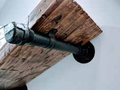 an industrial pipe is mounted to the side of a wooden beam with metal fittings