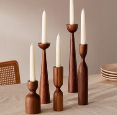 a group of wooden candlesticks sitting on top of a table next to plates