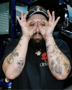 a man with tattoos covering his eyes and holding his hands in front of his face