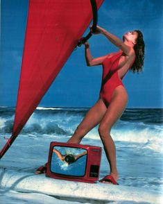 a woman in a red swimsuit holding a sail while standing next to a tv