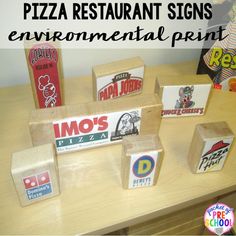 pizza restaurant signs are made out of cardboard boxes on a table in front of a child's playroom