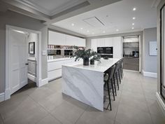 a large kitchen with marble counter tops and bar stools next to an open floor plan