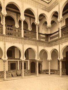 an old photo of a building with columns and arches on the inside, looking into the courtyard