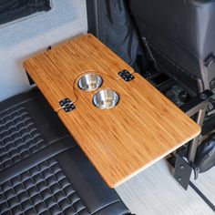 a wooden table with two bowls on it in the back of a truck or van