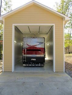 a small garage with a red bus in it's door and another truck parked inside