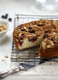 a close up of a cake on a cooling rack with a slice missing from it