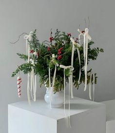 a white vase filled with greenery and candy canes on top of a table