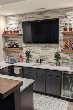 a kitchen with black cabinets and white countertops has a flat screen tv on the wall