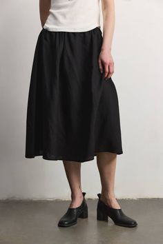 The Agnes Skirt is a timeless piece designed for comfort and style. Crafted from a light linen blend fabric, this midi skirt features a full silhouette and an adjustable drawstring waist for a personalized fit (can stretch an additional 3"). Fabric: 70% Tencel, 30% Linen Riley is 5'10" and wearing a size S (32" Bust, 24" Waist, 35" Hips) Measurements: Small (waist 13.5", length 28") Medium (waist 15", length 28.5") Large (waist 16", length 29") Black Knee-length Skirt With Elastic Waistband, Black Cotton Midi-length Bottoms, Black Cotton Midi Bottoms, Knee-length Black Skirt For Daywear, Relaxed Drawstring Skirt For Work, Relaxed Midi Skirt With Drawstring, Black Cotton Knee-length Skirt, Black Knee-length Cotton Skirt, Casual Linen Midi Bottoms